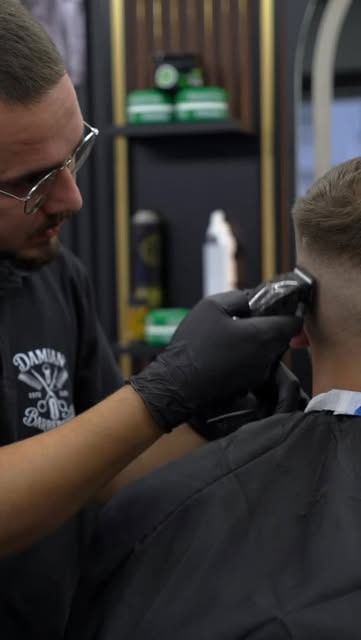 Barbier rasiert mit dem Trimmer einen sauberen Fade bei Damian Barber